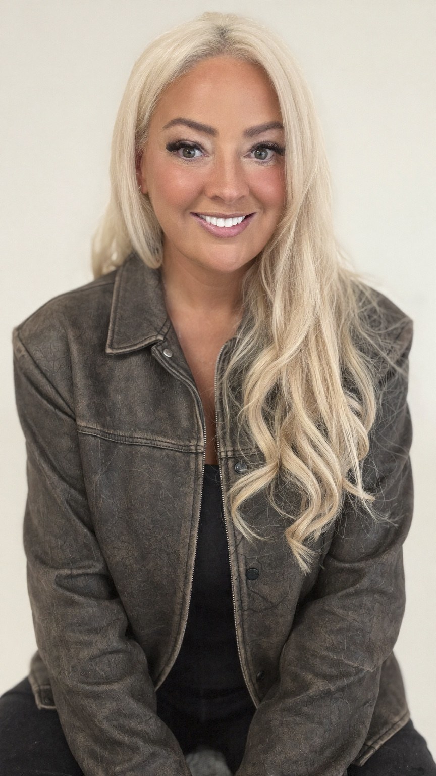 Claire Sinclair smiling, with long blonde hair and a charcoal denim jacket.