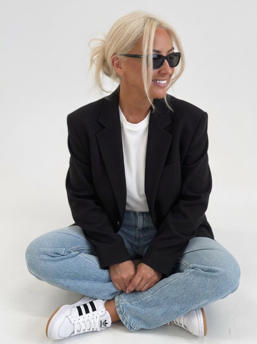 Claire sitting cross legged, smiling in sunglasses.
